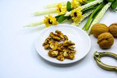 食品 食物 植物 果实 成熟的 特写 绿色食品 美味 零食 坚果 干果 核桃 核桃仁 膳食纤维 小吃 益智 亚洲 健康食物 有机食品 膳食 养生 滋补 营养 食材 生活方式 健康的 白色背景 白瓷盘 干果钳 简单背景
