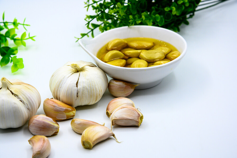 蒜与泡蒜 蒜 泡蒜 糖蒜 白醋糖蒜 泡菜 咸菜 小菜 腌渍 腌制 泡 咸的 咸香 辣 蔬菜 植物 芥菜根茎 芥菜头 佐料 萝卜 豇豆 发酵 黄瓜 咸菜疙瘩 下饭菜 中国传统食品 酱汁 白盘子 玻璃瓶 玻璃器皿 切开 切碎 辣椒 红辣椒 红色 绿色 青色 瓷碗 白色瓷碗 瓷盘 盘子 绿叶 白色背景
