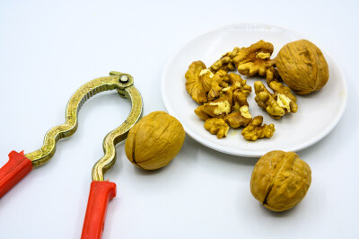 食品 食物 植物 果实 成熟的 特写 绿色食品 美味 零食 坚果 干果 核桃 核桃仁 膳食纤维 小吃 益智 亚洲 健康食物 有机食品 膳食 养生 滋补 营养 食材 生活方式 健康的 白色背景 白瓷盘 干果钳 简单背景
