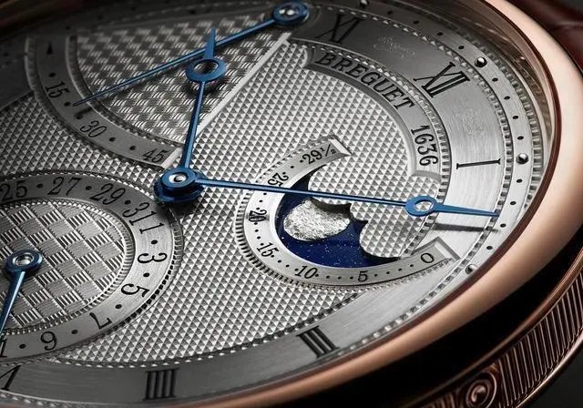 宝玑（BREGUET）2020经典系列7137腕表（玫瑰金表壳）（局部）
以篮织纹标示动力储备显示区域、以棋盘纹呈现日期显示并以巴黎钉纹装饰表盘的主要部分。白色金款的表盘呈宝玑蓝色，玫瑰金款的表盘颜色则由银粉配合软刷打造而成。
7137参数：18K白金或玫瑰金表壳，带有钱币纹装饰，圆形焊接式表耳，以螺丝栓固定。直径39毫米，厚度8.65毫米，防水深度30米。
7137新款搭载502.3 QSE1机芯，硅质平游丝，镌刻独立编号与宝玑签名。18K金质摆陀饰有手工玑镂刻花装饰。