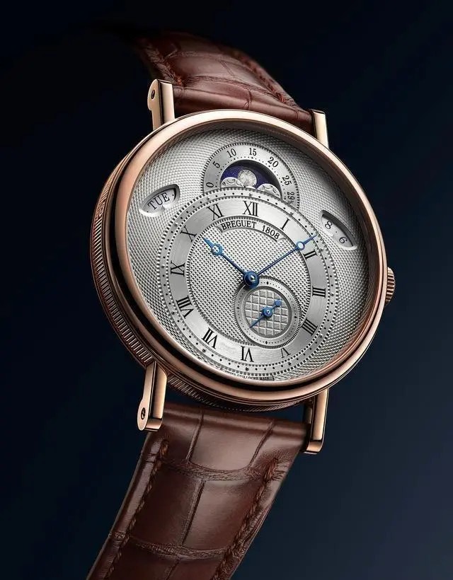 宝玑（BREGUET）2020经典系列7337双历月相款腕表（玫瑰金表壳）
经典系列7337腕表的表盘以环形排布的大麦纹润饰小时刻度圈边缘，棋盘纹装饰小秒盘，而巴黎钉纹则镌刻于表盘中央。
月相盈亏显示窗的漆面星空中环绕镌刻着云朵图案，其间点缀着璀璨光芒，包裹着以明亮的浮雕及磨砂凹槽描绘的月亮。10点钟位置及2点钟位置设有两个视窗，用于显示日期与星期。
7337参数：18K白金或玫瑰金表壳，带有钱币纹装饰，圆形焊接式表耳，以螺丝栓固定。直径39毫米，厚度9.9毫米，防水深度30米。