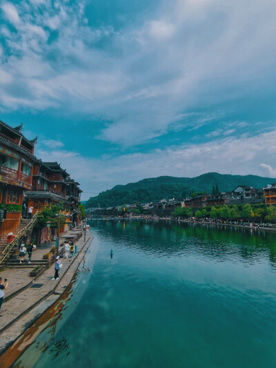 凤凰，北门古城楼、石板老街、风雨桥、沱江两岸的吊脚楼是这座城市的历史印记，清澈的沱江水缓缓从古城中间穿过，踏着石墩从沱江上走过，感受清凉一夏；夜晚，寻一处临江酒吧，看着两岸灯光倒映在江面，听着歌，喝着…