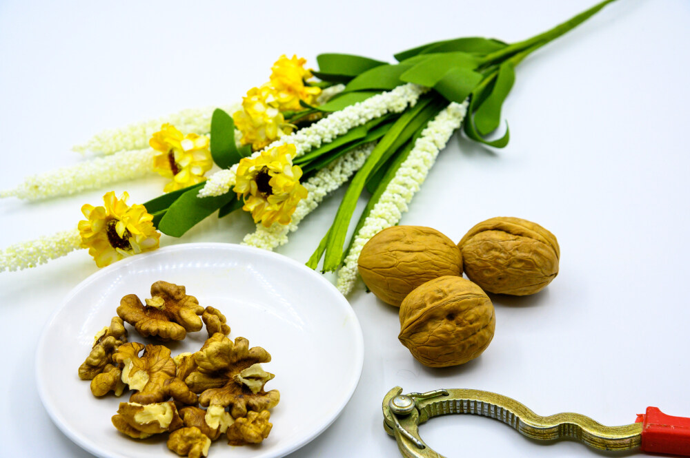 食品 食物 植物 果实 成熟的 特写 绿色食品 美味 零食 坚果 干果 核桃 核桃仁 膳食纤维 小吃 益智 亚洲 健康食物 有机食品 膳食 养生 滋补 营养 食材 生活方式 健康的 白色背景 白瓷盘 干果钳 简单背景
