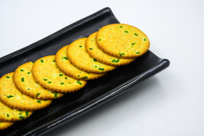 葱油饼干 葱 葱花 大葱 食用油 植物油 饼干 蛋 鸡蛋 卵 小麦 白面 蒸 熟的 甜点 糕点 点心 面点 蜂蜜 甜蜜 分享 烤 烘焙 食物 食品 美食 美味 膳食 饮食 黑色瓷盘 容器 瓷盘 长方形 装饰 白色 白色背景 吃 中国传统…