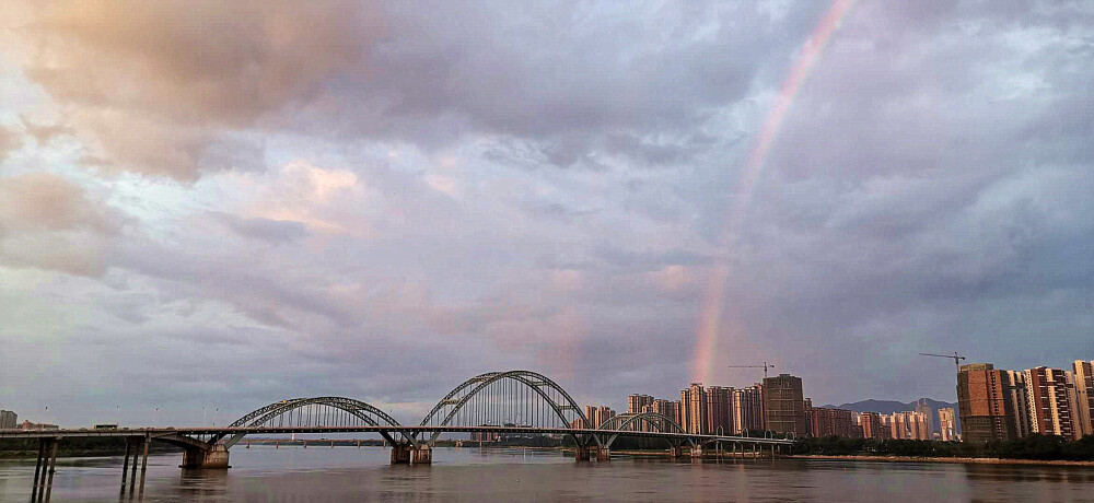 6月25傍晚时分，一场雨过后，江西吉安城区上空突然出现一道壮丽大彩虹，彩虹与空中的云彩、与高楼建筑、吉安大桥、赣江交相辉映，构成一幅美丽的风光大片。这一奇特的自然现象，吸引了许多市民驻足观望，并把这罕见的美景拍摄下来。（摄/肖勇）