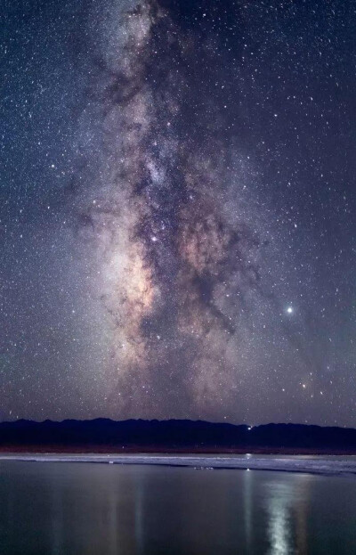 青海的茶卡盐湖，夜幕低垂，
闪烁的繁星在静谧的湖面上留下清晰的倒影，
银河宛如明亮的牛奶瀑布一般展现在面前，
似乎伸出手便可以触摸到。