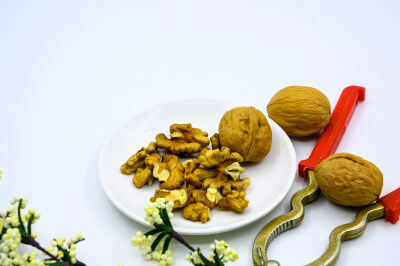 食品 食物 植物 果实 成熟的 特写 绿色食品 美味 零食 坚果 干果 核桃 核桃仁 膳食纤维 小吃 益智 亚洲 健康食物 有机食品 膳食 养生 滋补 营养 食材 生活方式 健康的 白色背景 白瓷盘 干果钳 简单背景
